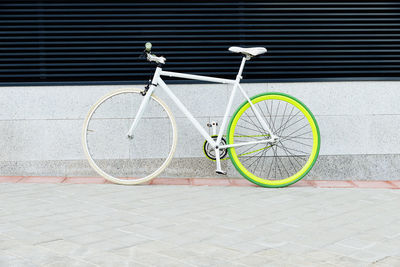 Bicycle parked on footpath against wall