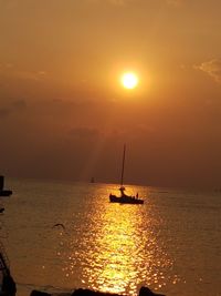 Silhouette sailboat in sea against sky during sunset