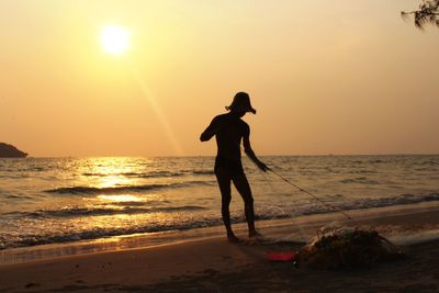 Silhouette of fisherman with fishing net on beach