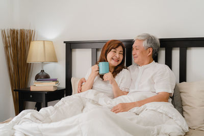 Woman sitting on bed at home