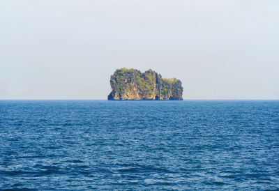 Rock formation in sea against clear sky