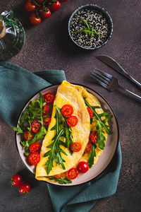 Omelette pancake with cherry tomatoes and arugula on a plate on the table top and vertical view