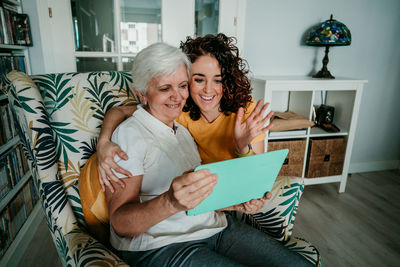 Smiling woman and daughter on video call over digital tablet