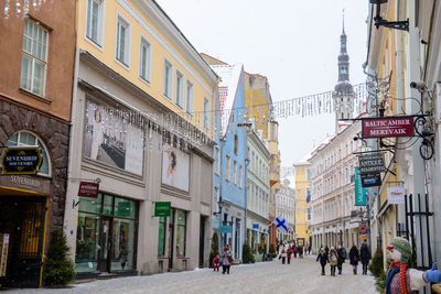 People walking on road amidst buildings in city