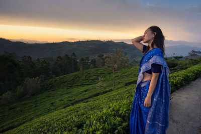 Woman standing on mountain against sky during sunset