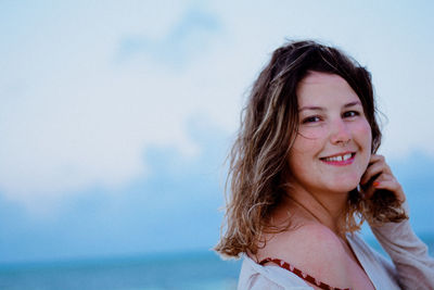 Portrait of smiling young woman against sky