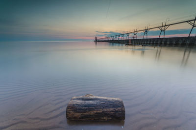 Bridge over sea against sky during sunset