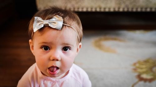 Close-up portrait of cute baby girl wearing headband at home