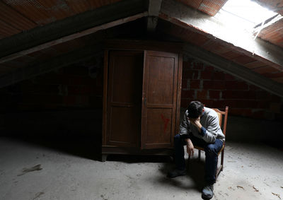 Full length of man sitting in abandoned building