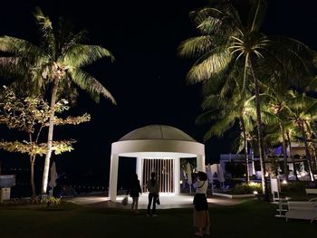 People standing by swimming pool at night