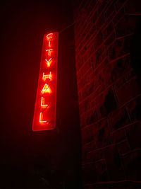 Low angle view of illuminated sign on wall at night