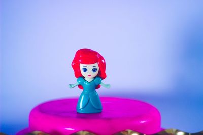 Close-up of toy on pink table against blue background