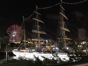 Illuminated ferris wheel against sky in city at night