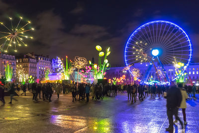 Illuminated ferris wheel in city at night