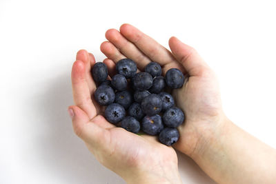 Cropped image of hand holding fruit against white background