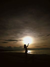 Optical illusion of woman holding sun at beach against sky