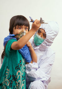 Doctor with girl wearing mask against white background