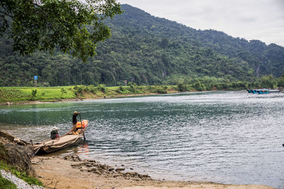 People on boat in sea against mountains