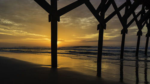 Silhouette trees on beach against sky during sunset