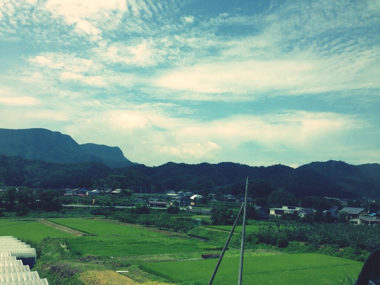 mountain, landscape, sky, mountain range, tranquil scene, scenics, grass, tranquility, beauty in nature, cloud - sky, field, building exterior, nature, cloud, green color, built structure, architecture, house, rural scene, village