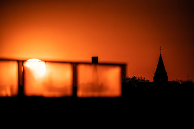 Silhouette temple against building during sunset