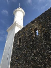 Low angle view of lighthouse by building against sky