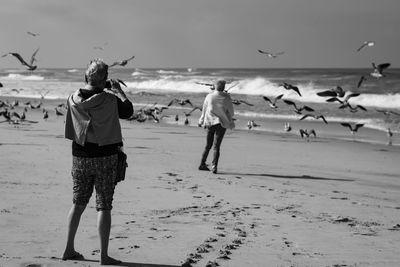 Full length of friends standing on beach against sky