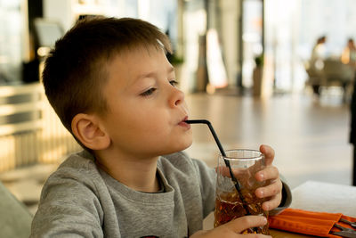 Close-up of boy drinking juice at cafe