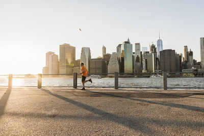 Man and buildings in city against clear sky