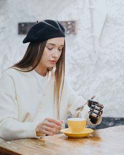 Young woman using mobile phone while sitting on table