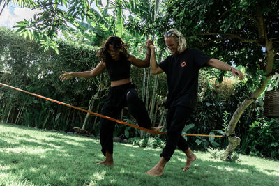 Full length of friends enjoying plants against trees