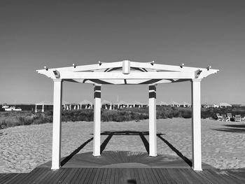 Information sign on pier at beach against clear sky