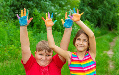 Smiling girl and boy with colored palm of hands