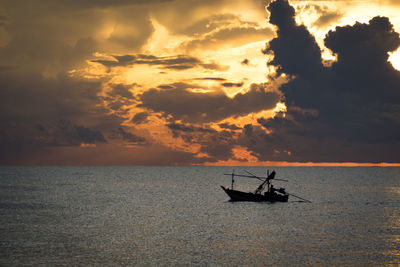 Silhouette man sailing in sea against sky during sunset