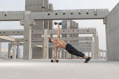 Muscular shirtless man exercising outdoors