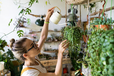 Close-up of woman watering plants in workshop