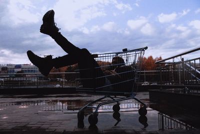 Man sitting in shopping cart in city