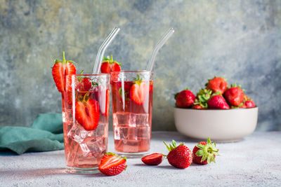 Refreshing cocktail with strawberries in glasses with a straw on the table and a bowl with berries