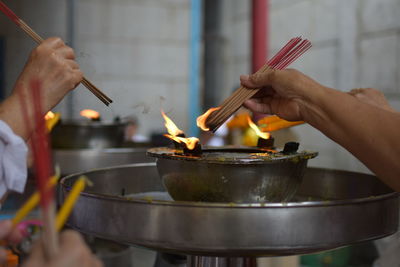 Cropped hands of people burning incense