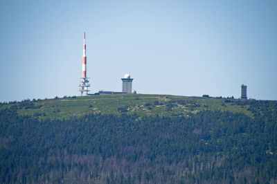 Lighthouse on field by building against clear sky