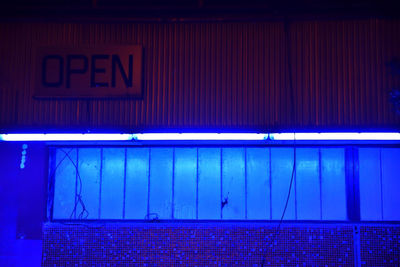 Close-up of illuminated text on blue wall