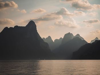 Scenic view of sea and silhouette mountains against sky