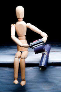 Close-up of wooden figurine with camera film against black background