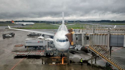 Airplane on airport runway against cloudy sky