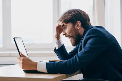 Side view of young man using laptop on table