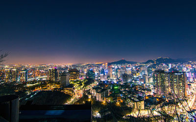 High angle view of illuminated buildings against clear sky at night