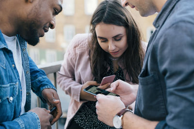 Friends looking at man using smart phone in city