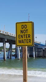 Information sign on beach against clear blue sky