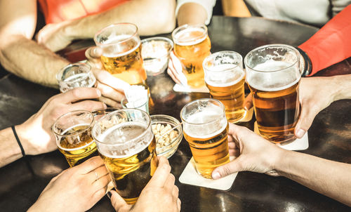 Cropped hands of friends toasting beer at restaurant