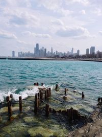 Scenic view of sea by cityscape against sky